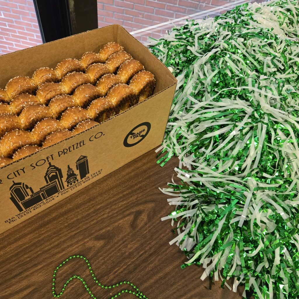 Philly soft pretzels in a box next to green and white pom poms.