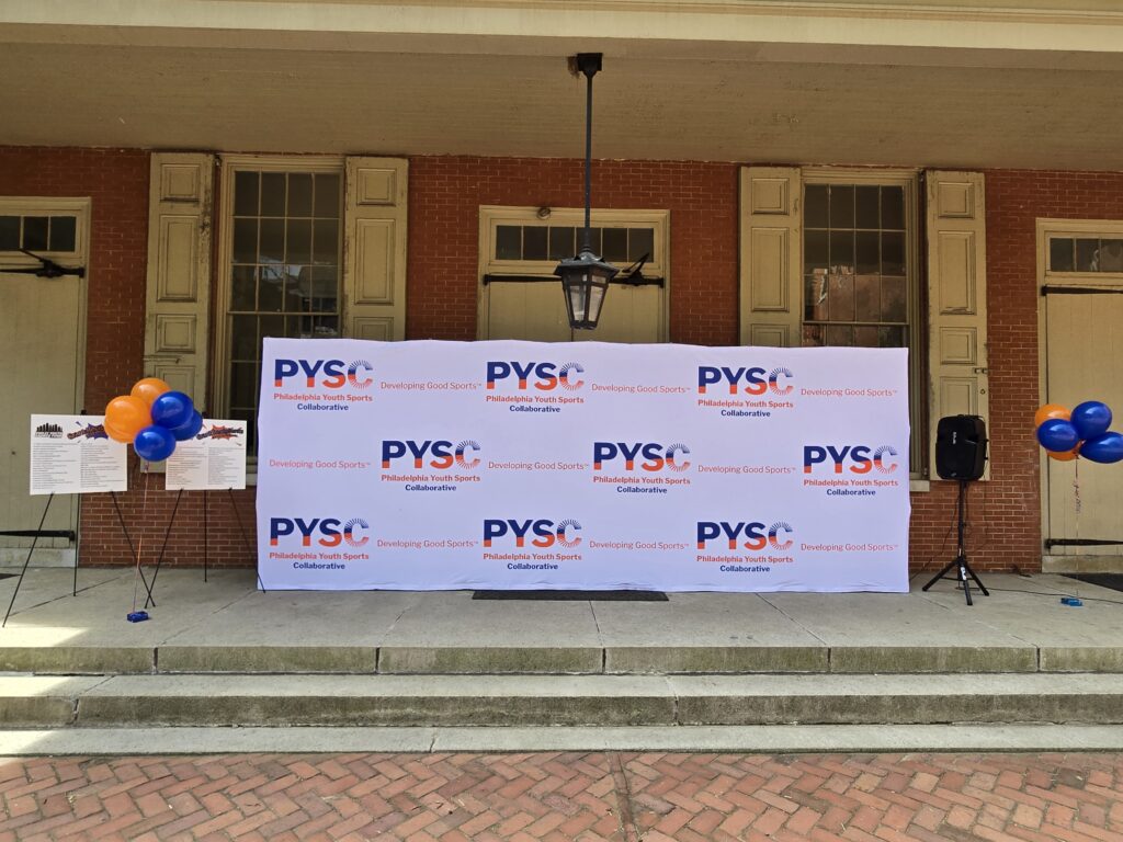 A PYSC photo backdrop is in front of the Race Street Quaker Meetinghouse.